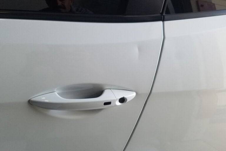 Door ding beside the handle on a white car door
