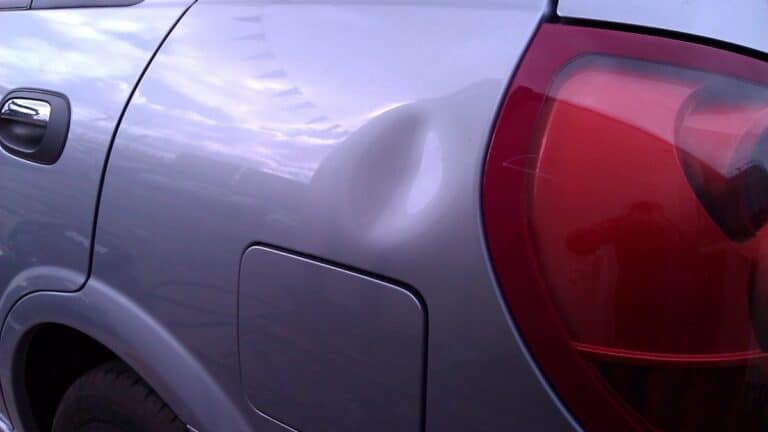 Dent beside the taillight on a car rear quarter panel before repair