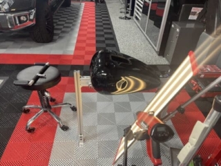 Black motorcycle fuel tank on PDR jig with light board for dent removal assessment at RPM Dent Repair