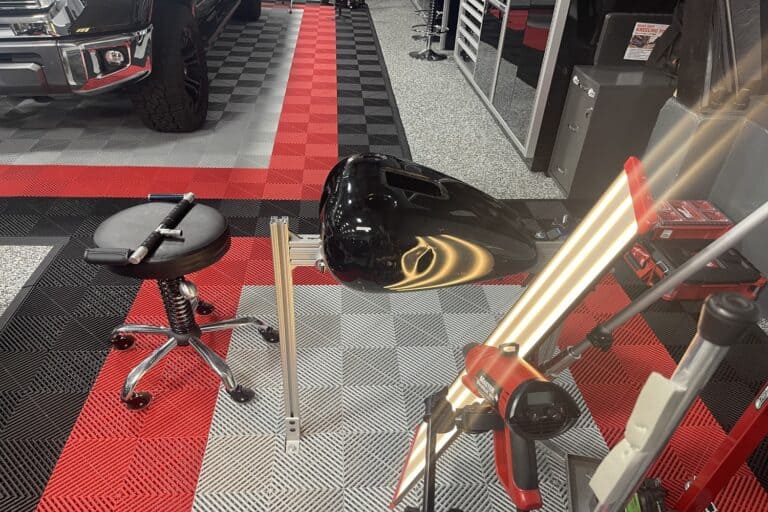 Black motorcycle fuel tank on PDR jig with light board for dent removal assessment at RPM Dent Repair