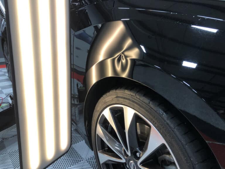 Wheel-Arch Panel Dent on a Black Vehicle — PDR Raynham MA Dent on the body panel above the rear wheel arch of a black vehicle under PDR light at RPM Dent Repair Raynham Massachusetts