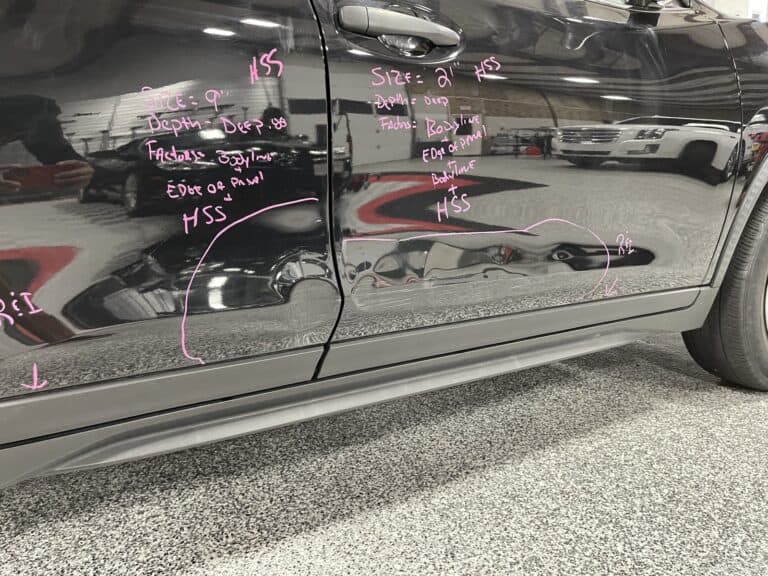 Dent Mapping — Damage Assessment Marks Before PDR Technician grease-pencil marks recording dent size depth and panel details on a black vehicle door before paintless dent repair at RPM Dent Repair Raynham Massachusetts