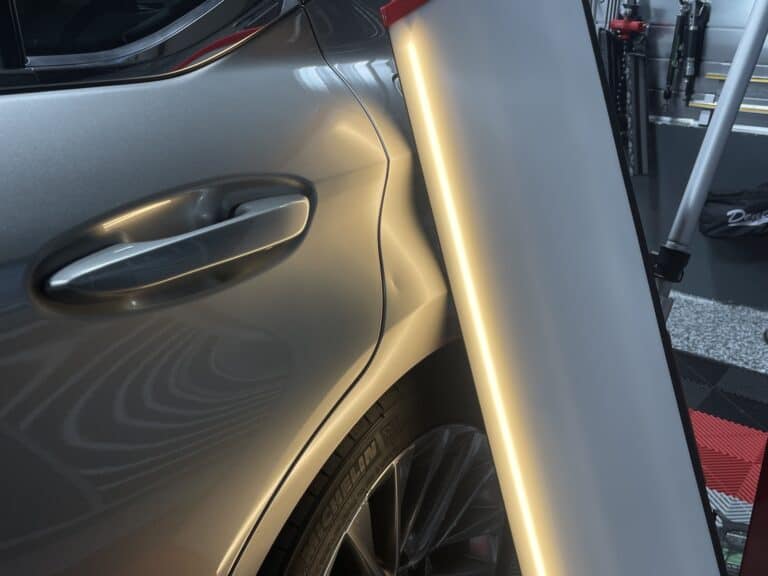Door ding dent on vehicle door panel near handle before paintless dent repair in Raynham MA