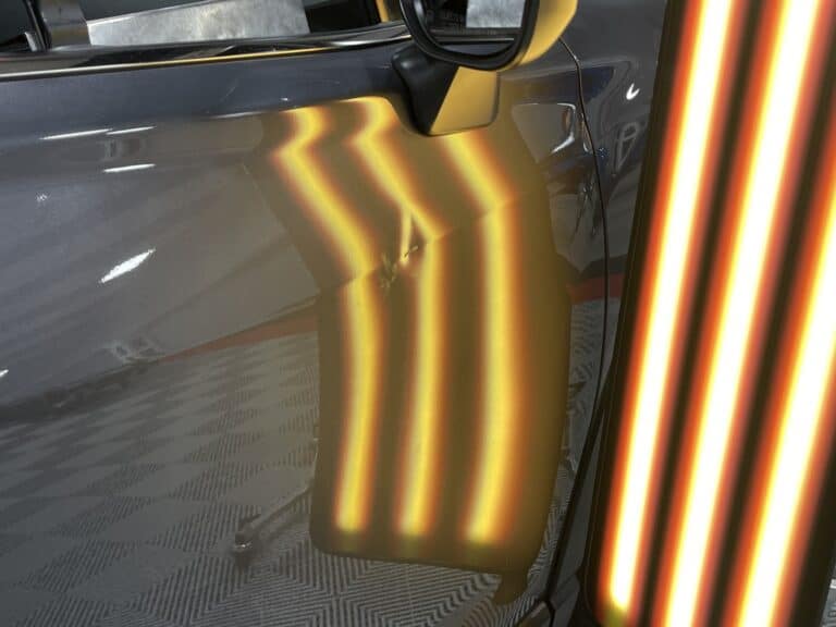 Dark Grey Door Panel Dent — PDR Raynham MA PDR light reflected across the dark grey front door panel of a vehicle showing a sharp dent at RPM Dent Repair Raynham Massachusetts