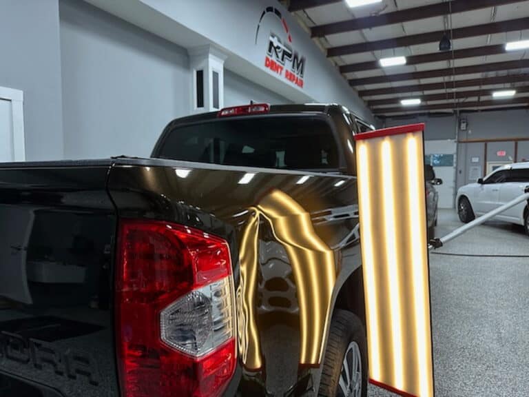 Black truck bed with large dent before paintless dent repair &mdash; PDR light assessment at RPM Dent Repair Raynham MA